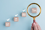 Lupe vergrößert Holzklotz mit Aufschrift Tax